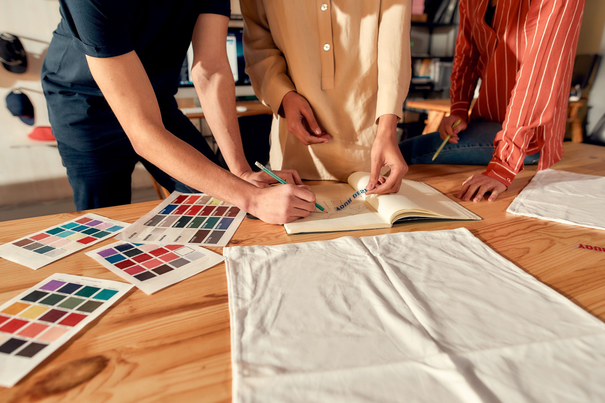 The power of us. Cropped shot of designers drawing sketches, while creating logo and design of T-shirt. Young man and women working together at custom T-shirt, clothing printing company