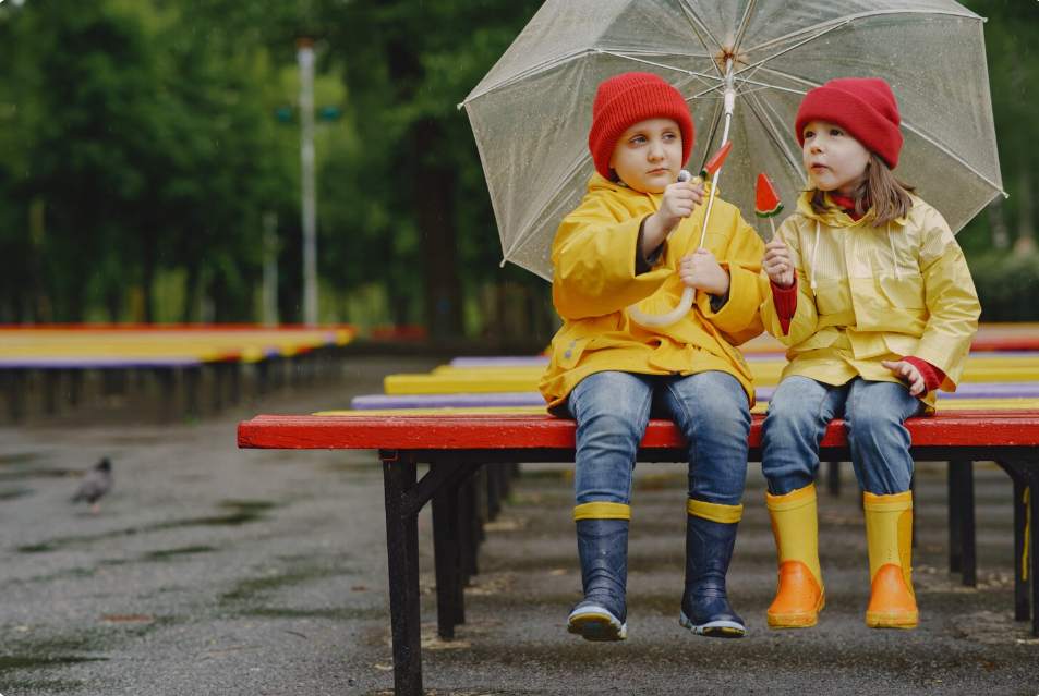 kids in rain boots playing in a rainy park