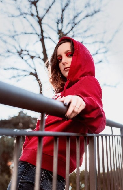 Portrait of woman in hoodie standing by railing
