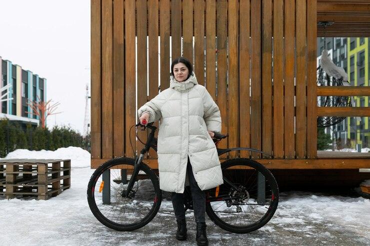 Woman standing next to bike in snow